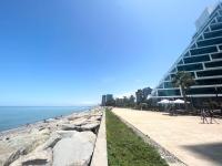 a sidewalk next to a beach with a building at Beachfront Batumi View Apartments by GLOBALSTAY in Batumi