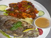 un plato de comida con pescado y verduras y una salsa en Abenab Lodge & Tours cc, en Groutfontein