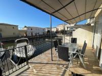 a balcony with a table and chairs and a boat at Résidence quai St Louis Villa t4 pour 6 personnes N1 47 in Aigues-Mortes
