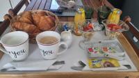 a tray with two cups of coffee and a basket of bread at Chambres d&#39;hôtes avec jacuzzi privatif in Westrehem