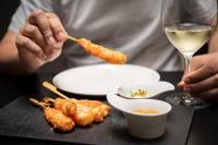 Una persona está comiendo comida con una copa de vino. en Hotel Plaza, en A Coruña