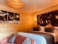 a bedroom with a bed and a couch and a chandelier at Hotel Le Panorama in Le Mont-Dore