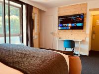 a hotel room with a bed and a flat screen tv at Hotel Le Panorama in Le Mont-Dore