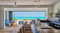 une salle à manger avec un long bar offrant une vue sur la plage dans l'établissement Grand Isle Resort & Residences, à Farmerʼs Hill