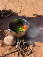 a pot of vegetables sitting on the beach at Rum Under The Stars Camp in Wadi Rum