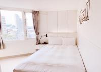a white bedroom with a bed and two windows at Kiwi Express Hotel - Zhong Zheng Branch in Taichung