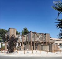 a building with a wooden structure on the side of it at Mobil-home (Clim, Tv)- Camping Narbonne-Plage 4* - 022 in Narbonne-Plage