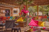 a patio with a statue of a pink flamingo and chairs at Mobil-home (Clim, Tv)- Camping Narbonne-Plage 4* - 022 in Narbonne-Plage