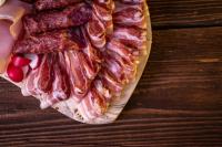 a plate of bacon and sausage on a wooden table at Lorettohof Hotel Garni in Gaal