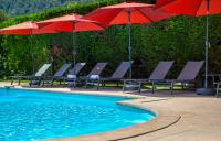 - une piscine bordée de chaises et de parasols rouges dans l&#39;établissement KYRIAD MARSEILLE EST - Aubagne Gémenos, à Gémenos