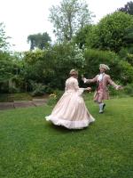 a man and a woman in dresses walking in the grass at L&#39;Orangerie White-Palacio in Versailles