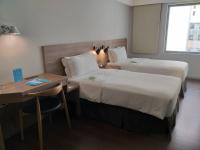 a hotel room with two beds and a desk at Just Sleep Kaohsiung Zhongzheng in Kaohsiung