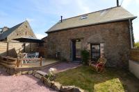 a stone house with a patio with a table and an umbrella at La porcherie du pet en l&#39;air in Saint Malo