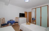 a room with two beds and a tv and chairs at Apartmani Krmek in Mlini