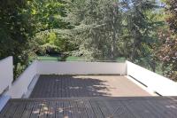 a wooden deck with a white wall and trees at Maginifique villa d&#39;architecte sur les bords de Marne tout près de Paris in Le Perreux-Sur-Marne