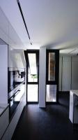 a kitchen with white walls and black floors and windows at Maginifique villa d&#39;architecte sur les bords de Marne tout près de Paris in Le Perreux-Sur-Marne