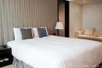 a bedroom with a large white bed and a chair at Talmud Hotel Kaohsiung LoveRiver in Kaohsiung