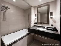 a bathroom with a bath tub and a sink and a mirror at Talmud Hotel Kaohsiung LoveRiver in Kaohsiung