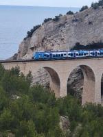 a blue train on a bridge over a mountain at La Villa de Niolon au coeur de la calanque vue mer in Le Rove