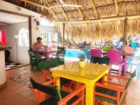 een restaurant met kleurrijke tafels en stoelen en een zwembad bij Divanga Hostel and Diving in Taganga