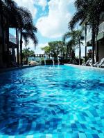 a large swimming pool with blue water and palm trees at Destini Akef Villa in Pantai Cenang