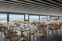 ein Esszimmer mit Tischen, Stühlen und Fenstern in der Unterkunft Ramada Plaza By Wyndham Batman in Batman