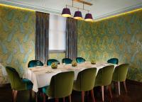 uma sala de jantar com uma mesa longa e cadeiras verdes em Taj 51 Buckingham Gate Suites and Residences em Londres