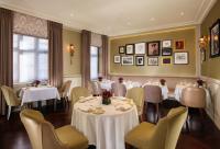 uma sala de jantar com mesas e cadeiras brancas em Taj 51 Buckingham Gate Suites and Residences em Londres