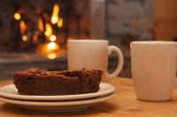 a piece of chocolate cake on a plate next to two cups at L&#39;Aiglon - spacious 2-bedroom apartment with log fire in Sainte-Foy-Tarentaise