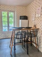 a table with two chairs and a refrigerator in a room at Élégante &amp; Design Casa Churchill - Brive Centre in Brive-la-Gaillarde