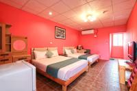 a red room with two beds and a woman sitting on a chair at Fumigate Hotel in Hengchun South Gate