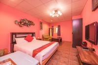 a bedroom with pink walls and a bed and a flat screen tv at Fumigate Hotel in Hengchun South Gate