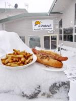 a hot dog and french fries on a table with snow at Sundeck Hotel in Perisher Valley