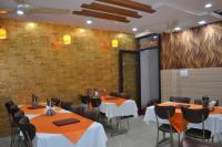 Un comedor con mesas y sillas y una pared. en Hotel Jigyasa By Mayda Hospitality Pvt. Ltd., en Agra