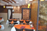 comedor con mesas, sillas y espejo en Hotel Jigyasa By Mayda Hospitality Pvt. Ltd., en Agra