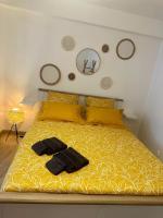 a bed with a yellow comforter and a black robe on it at Appartement neuf entièrement équipé proche centre in Amiens