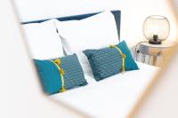 - un lit blanc avec des oreillers bleus et une lampe dans l&#39;établissement Charmant Studio Climatisé &#39;Alma 1&#39; - Béziers Centre - Wifi Fibre - Netflix, à Béziers