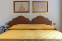 a bed with a yellow blanket and two pictures on the wall at Hotel Casa Boccassini in Venice