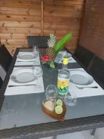 una mesa con platos y una botella de vino y una piña en Beau T2 Cosy tout Confort avec terrasse et jardin, en Les Abymes