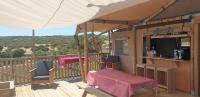 a house with a table and a television on a deck at Larah Land 4 Star Glamping Yala Lodge plus kids lodge in Šimuni