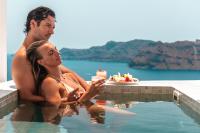 a man and a woman sitting in a swimming pool at Aspaki by Art Maisons in Oia