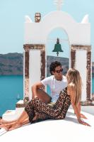 a man and a woman sitting on a ledge near the water at Aspaki by Art Maisons in Oia