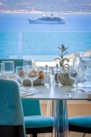 a table with glasses and a boat in the water at Hotel Saint Christophe in Calvi