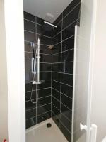 a bathroom with a shower with a black tiled wall at LE MEDITERRANEEN *T2 (40m²) *WIFI*PARKING PRIVE* in Lourdes