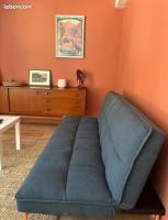 a blue couch in a living room with an orange wall at Appartement idéalement situé Font romeu in Font-Romeu-Odeillo-Via