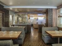 a restaurant with wooden tables and gray booths at Hotel Radana Vashi Navimumbai in Navi Mumbai