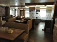 a restaurant with a table and chairs and a counter at Hotel Radana Vashi Navimumbai in Navi Mumbai