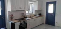 a kitchen with white cabinets and a blue door at Diakofti house by the sea - Kythoikies hoilday houses in Kythira