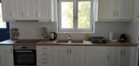 a kitchen with white cabinets and a sink and a window at Diakofti house by the sea - Kythoikies hoilday houses in Kythira