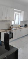 a white kitchen with white cabinets and a sink at Diakofti house by the sea - Kythoikies hoilday houses in Kythira